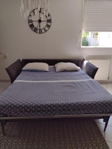 uma cama num quarto com um relógio na parede em Bienvenue dans beau T2 de 48m2 à Gennevilliers em Gennevilliers