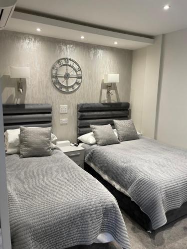 um quarto com duas camas e um relógio na parede em Park Avenue Hotel em Londres