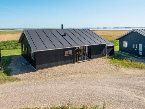 a black house with a black roof in a field at 8 person holiday home in Ulfborg in Thorsminde