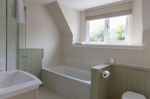 a bathroom with a bath tub and a window at Duart Cottage in Glencoe