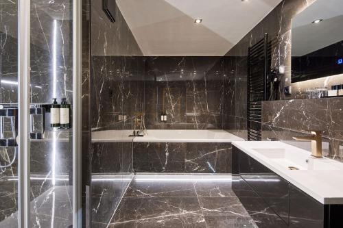 Van der Valk Golfhotel Serrahn - Adult Only في Serrahn: حمام مع دش ومغسلة وحوض استحمام