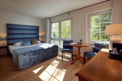 Schlafzimmer mit einem Bett, einem Tisch und Stühlen in der Unterkunft Van der Valk Golfhotel Serrahn - Adult Only in Serrahn