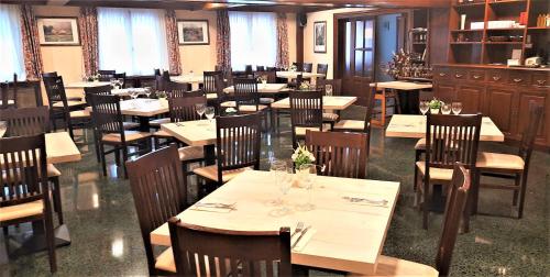 a dining room with tables and chairs in a restaurant at Hotel Urogallo in Vielha