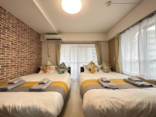two beds in a room with a brick wall at nestay apartment tokyo otsuka in Tokyo