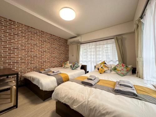 two beds in a room with a brick wall at nestay apartment tokyo otsuka in Tokyo