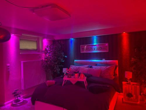 ゲーストハッハトにあるThailand Lounge Whirlpool Sauna SPAのピンクとブルーの照明が付いたベッドが備わる客室です。