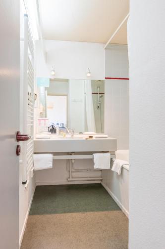 une salle de bain blanche avec un lavabo et un miroir dans l'établissement CERISE Dax - Les Jardins du Lac, à Saint-Paul-lès-Dax