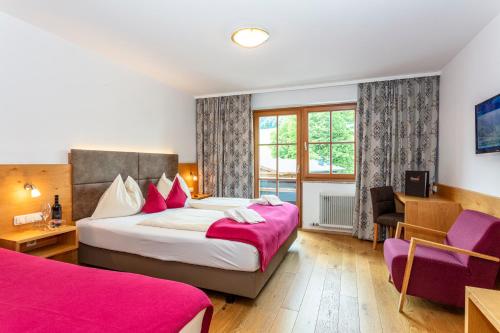 una habitación de hotel con 2 camas y una silla en Hotel Unser Unterberg, en Maria Alm am Steinernen Meer