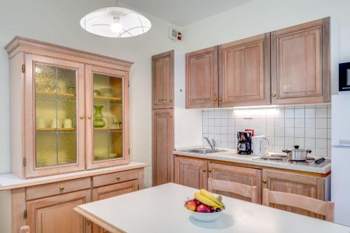 a kitchen with wooden cabinets and a bowl of fruit on a table at Residence La Filanda in Costermano sul Garda