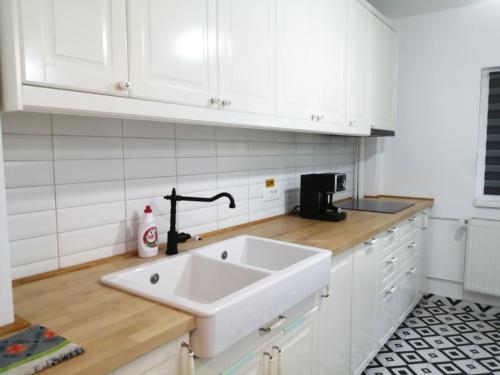 a kitchen with a white sink and white cabinets at Askade Residence Self Check-in in Bucharest