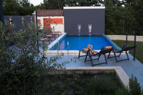 a swimming pool with chairs and a table next to it at Beautiful and private Villa Anka in Lokvičič
