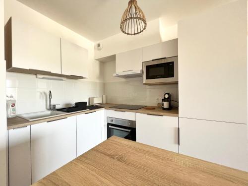 une cuisine blanche avec des armoires blanches et un micro-ondes dans l'établissement Joli appartement neuf La Ciotat, à La Ciotat