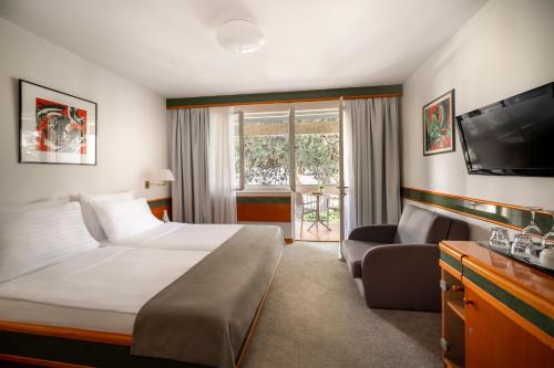 a hotel room with a bed and a tv and a couch at Maistra Select Pineta Hotel in Vrsar