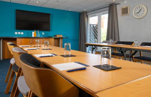 a conference room with tables and chairs and a flat screen tv at Holiday Inn Express Peterborough by IHG in Peterborough