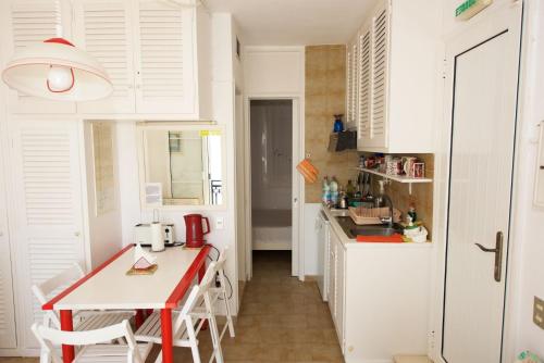 une cuisine avec une table rouge et des armoires blanches dans l'établissement Private Veranda to the Sea New Era Home 32 by New Era, à Glyfada
