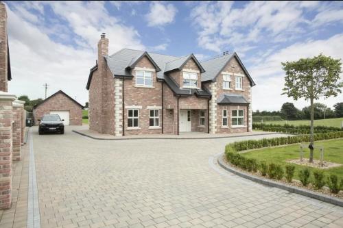 a large brick house with a car parked in the driveway at Louth Village Wedding Accommodation with Gym B&B in Lubhaidh