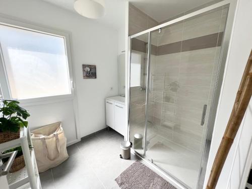 La salle de bains est pourvue d'une douche en verre et d'une fenêtre. dans l'établissement Joli appartement neuf La Ciotat, à La Ciotat
