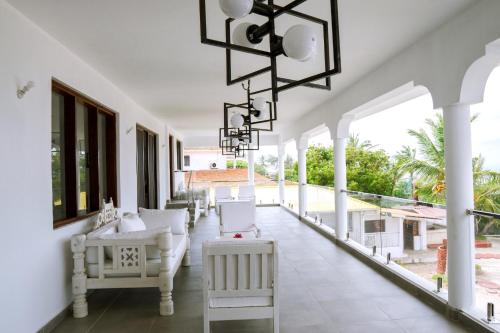 een witte veranda met witte stoelen en een kroonluchter bij Met Beach Resort Malindi in Malindi