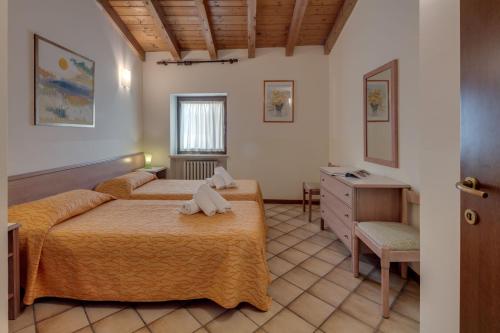 a bedroom with two beds and a dresser in it at Residence La Filanda in Costermano
