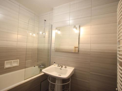 ein Badezimmer mit einem Waschbecken, einem Spiegel und einer Badewanne in der Unterkunft Appartement Chamrousse, 3 pièces, 8 personnes - FR-1-340-169 in Chamrousse