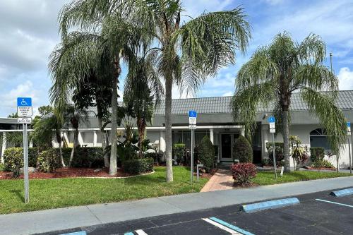a building with palm trees in front of a street at Ramada by Wyndham Cocoa in Cocoa