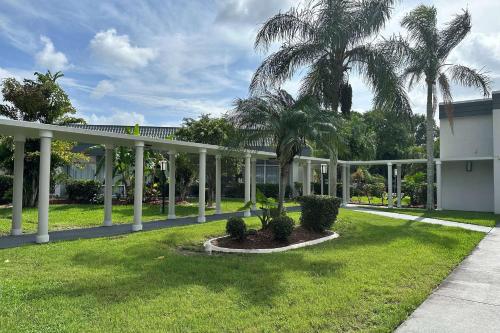 a white pavilion with palm trees in a yard at Ramada by Wyndham Cocoa in Cocoa