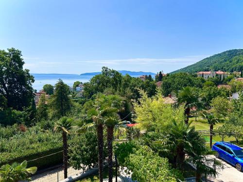 a blue car parked in a garden with palm trees at Apartments & Rooms Ribarić in Lovran