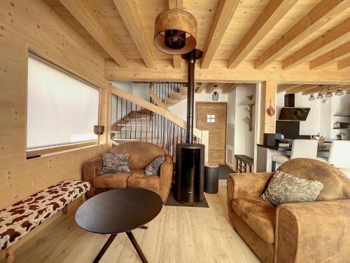 Elle comprend un salon doté d'un mobilier en cuir et d'un plafond en bois. dans l'établissement Chalet La Galise, à La Toussuire