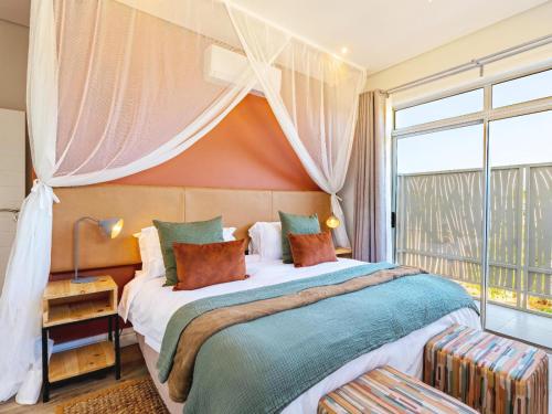 - une chambre avec un grand lit et une grande fenêtre dans l'établissement Miombo Mews, à Victoria Falls