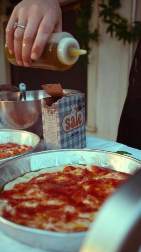 a person is pouring sauce into a pan of pizza at Casa Mita in Pulsano