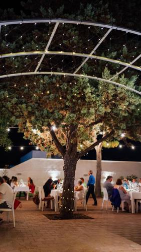 a group of people sitting at tables under a tree at Casa Mita in Pulsano