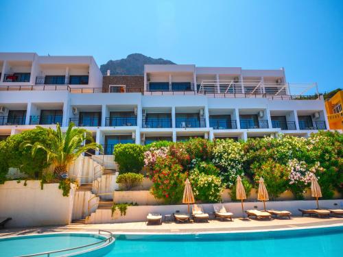 a hotel with a swimming pool with chairs and umbrellas at Plaza Hotel in Masouri