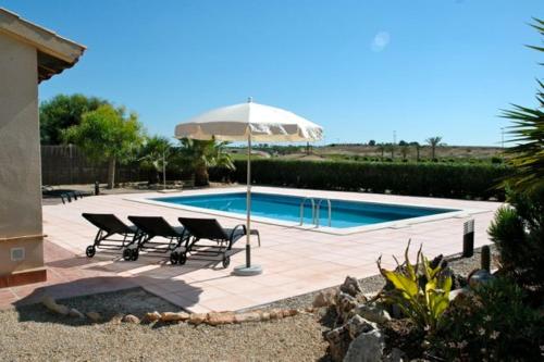 - un groupe de chaises et un parasol à côté de la piscine dans l'établissement HL 001 Holiday rentals 3 Bedrooms 2 Bathroom, à Fuente Alamo