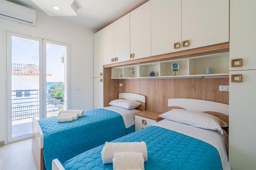 Dos camas en una habitación con una gran ventana. en Appartamento Greta vista mare, en Marina di Noto