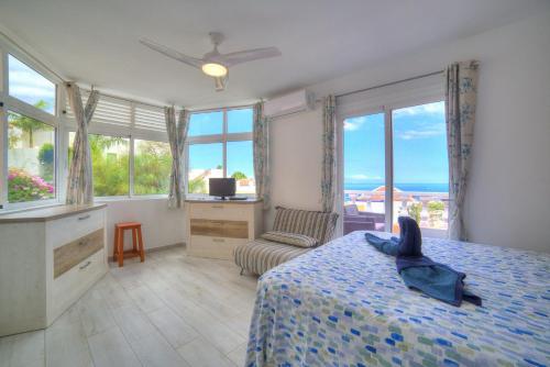 um quarto com uma cama com uma colcha azul e janelas em Ocean Hill - Ocean View, Terrace, BBQ, WIFI em Adeje