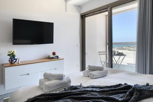 a bedroom with a bed with a flat screen tv at HaTsuk Beach Sea-View Studio by Sea N' Rent in Jlil