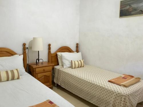 Apartamento Begur (costa brava) في بيغور: غرفة نوم بسريرين وطاولة بها مصباح