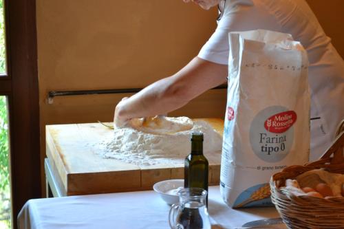 a person making a doughnut on a table with a bottle of wine at Relais Ciavatta Country Hotel in Montemerano