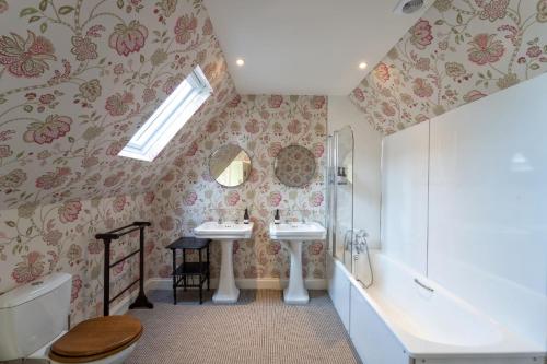 y baño con 2 lavabos, bañera y aseo. en Butley Priory Farmhouse 12 en Woodbridge