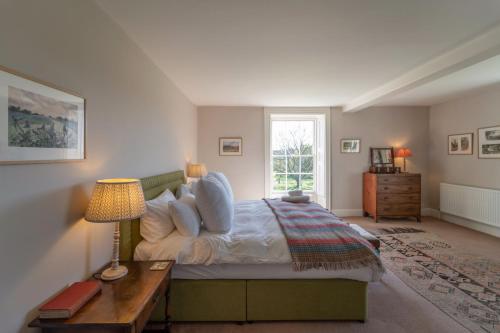 a bedroom with a bed with a table and a window at Butley Priory Farmhouse 12 in Woodbridge