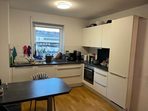 une cuisine avec des placards blancs, une table et une fenêtre dans l'établissement Schönes Zimmer in zentraler Lage, à Ulm