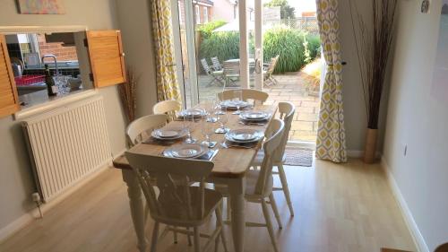 a dining room table with chairs and a table and a table at Poplars in Aldeburgh