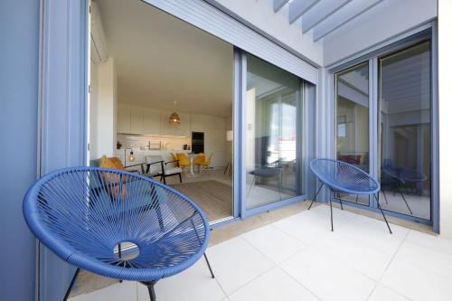 een patio met 2 blauwe stoelen en een woonkamer bij Casas do Forte Sun 4pax by Portugal Hideaway in Cabanas de Tavira