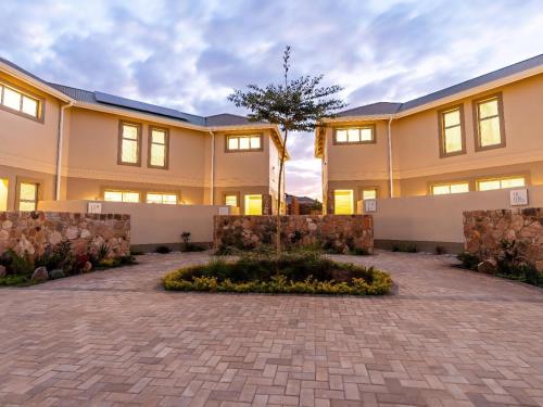 a large building with a brick driveway in front of it at Miombo Mews in Victoria Falls