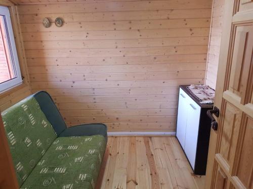 a small room with a green couch in a tiny house at Domek nad jeziorem Chańcza in Chańcza