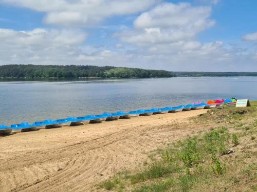 a long line of umbrellas on a beach next to the water at Domek nad jeziorem Chańcza in Chańcza