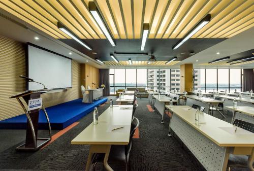 a conference room with tables and a projection screen at Riverine Place Hotel and Residence in Nonthaburi