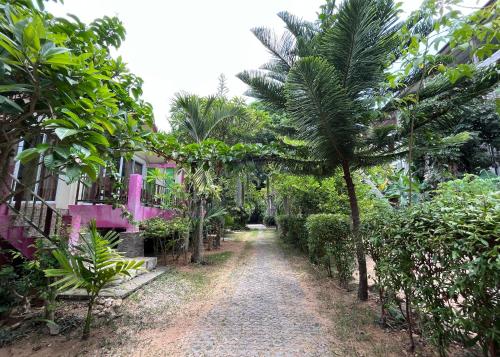 a dirt road in front of a house with palm trees at Mae Somboon House in Lamai
