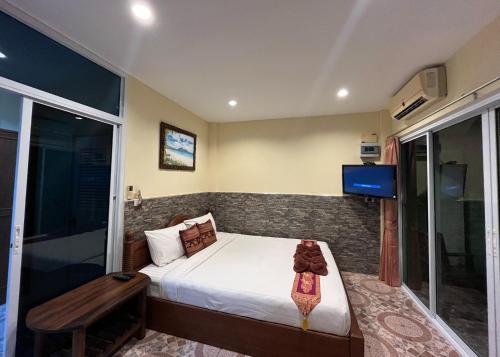 a bedroom with a bed and a tv on a wall at Mae Somboon House in Lamai