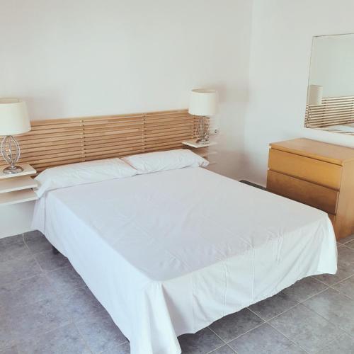 a bedroom with a white bed and a wooden headboard at Luminosa casa en Nerja in Nerja